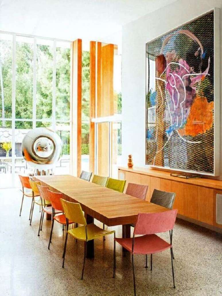28. Quadros grandes para sala de jantar decorada com mesa de madeira e cadeiras coloridas – Foto: Arkpad