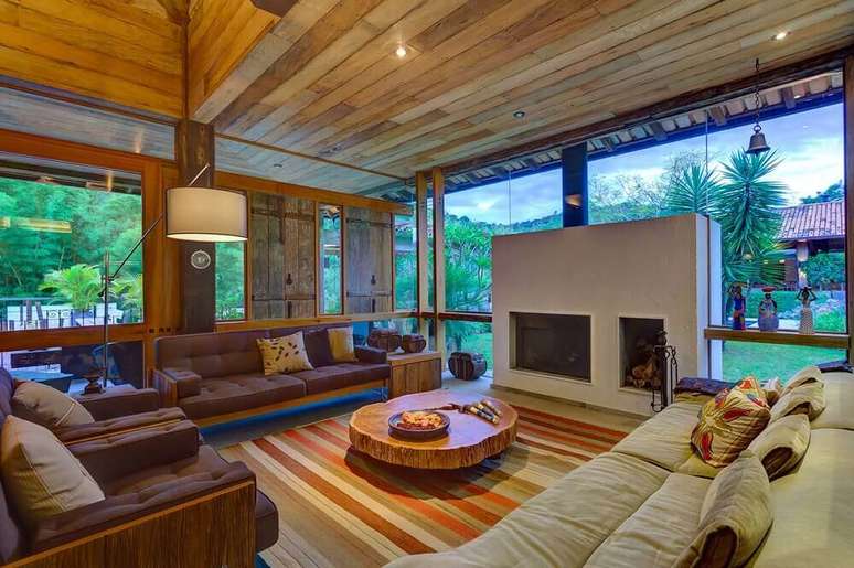 10. Casa de fazenda decorada com lumin&aacute;ria moderna e mesa de centro r&uacute;stica.