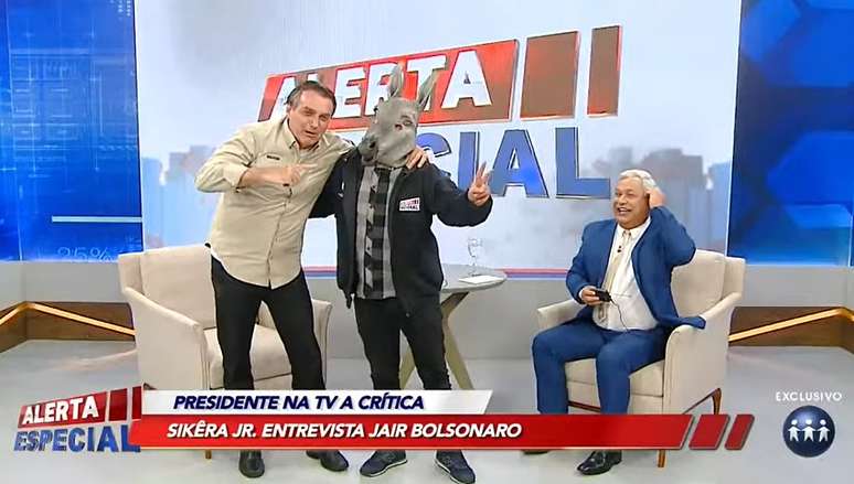 Bolsonaro faz graça ao lado do assistente de estúdio fantasiado de jumento no ‘Alerta Especial’ de Sikêra Jr.