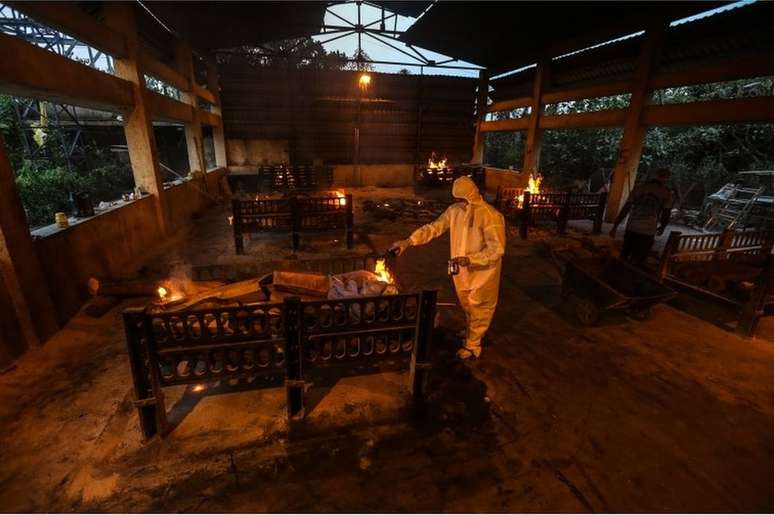 Parentes e funcionários municipais realizam os últimos ritos para as vítimas da covid-19 em local de cremação em Mumbai