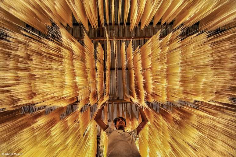 "Um trabalhador inspeciona se o macarrão de arroz secou corretamente"