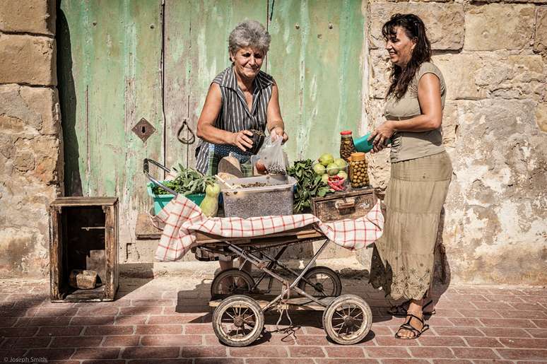 "Uma senhora vende alcaparras e outras iguarias de seu velho carrinho nas ruas de Marsaxlokk, uma vila de pescadores em Malta."