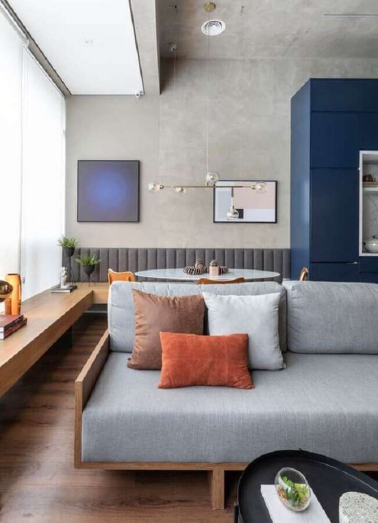 52. Decora&ccedil;&atilde;o estilo industrial com almofadas para sala com sof&aacute; de madeira e parede de cimento queimado &ndash; Foto: Archdaily