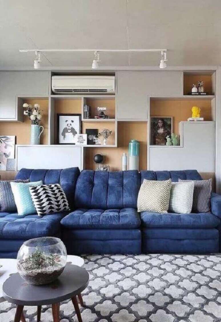 23. Almofadas diferentes para sala de TV moderna decorada com sofá azul e parede de nichos – Foto: Pinterest
