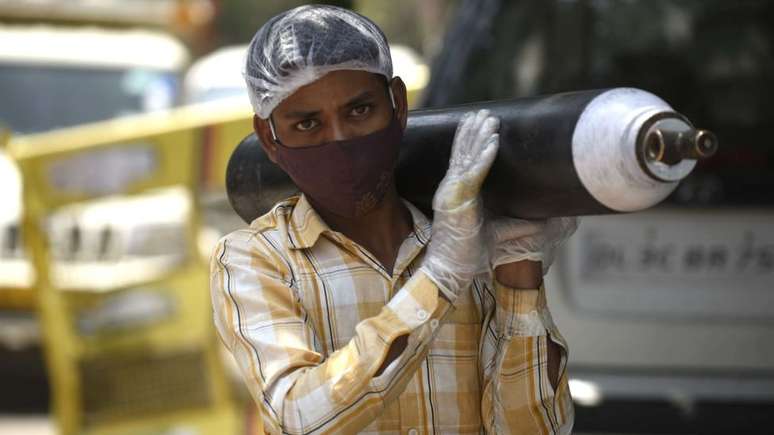 Uma pessoa esperando para reabastecer seu cilindro de oxigênio vazio em Gurgaon, Índia; cena aconteceu tanto no Brasil quanto no pais asiático