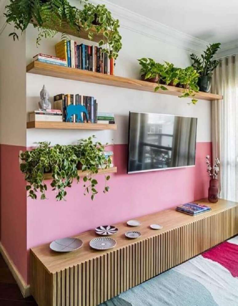 47. Pintura meia parede cor de rosa para sala de TV decorada com prateleiras e rack de madeira – Foto: Jeito de Casa