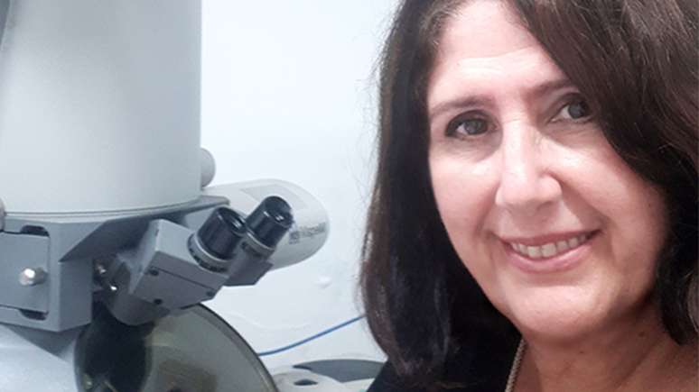 A bióloga e professora da FMUSP Elia Caldini. Ao fundo, o microscópio eletrônico, que aumenta dezenas de milhares de vezes as amostras de tecido para que os patologistas vejam o Sars-CoV-2