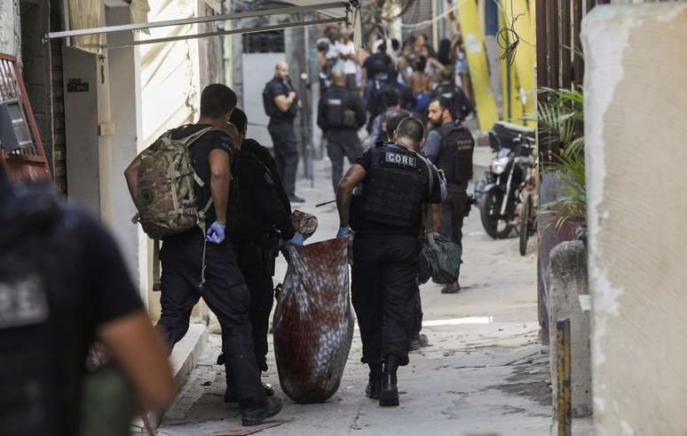 Policiais carregam corpo durante operação na favela do Jacarezinho