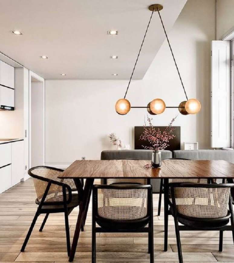 12. Decoração clean para sala de jantar com luminária moderna e cadeira com braço – Foto: Constance Zahn