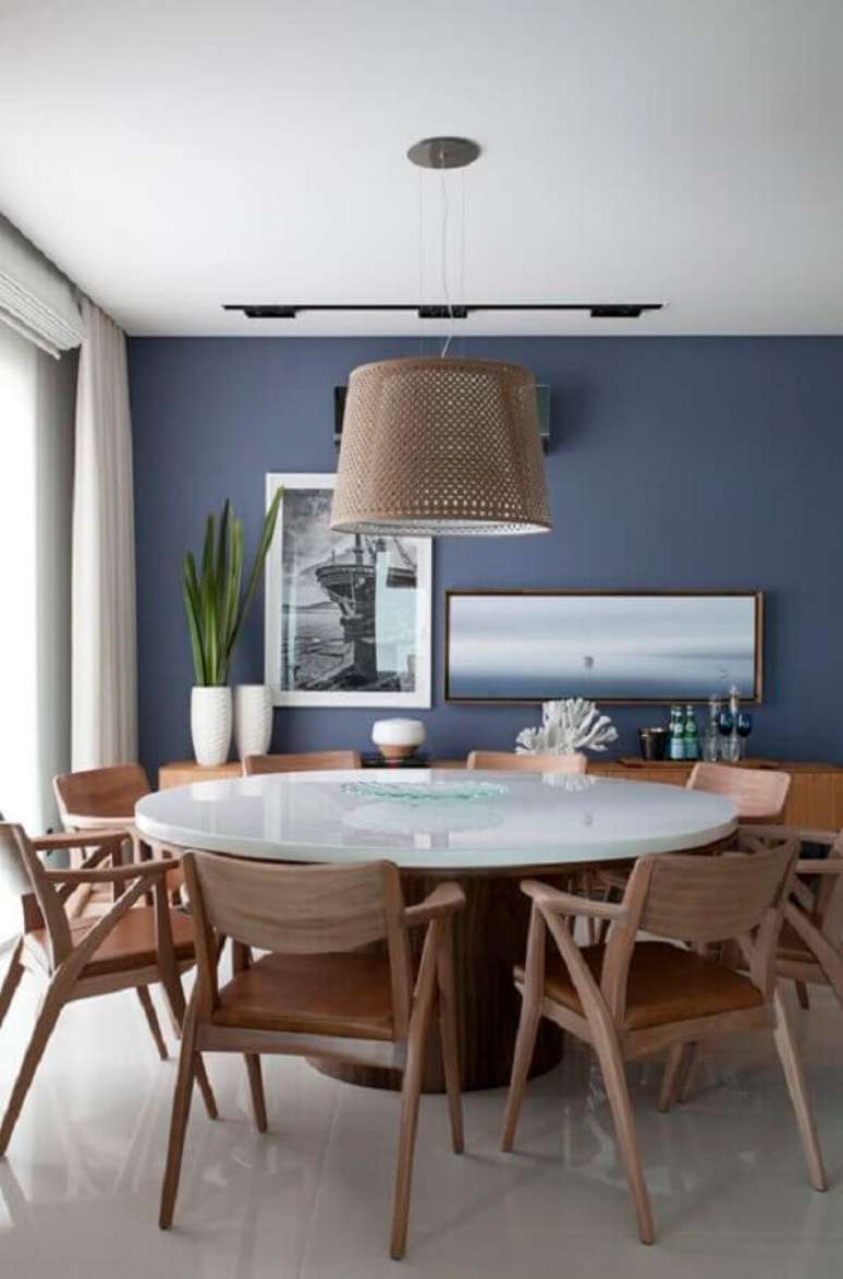 14. Cadeira com braço de madeira para sala de jantar decorada com mesa redonda e parede azul – Foto: Juliana Pippi