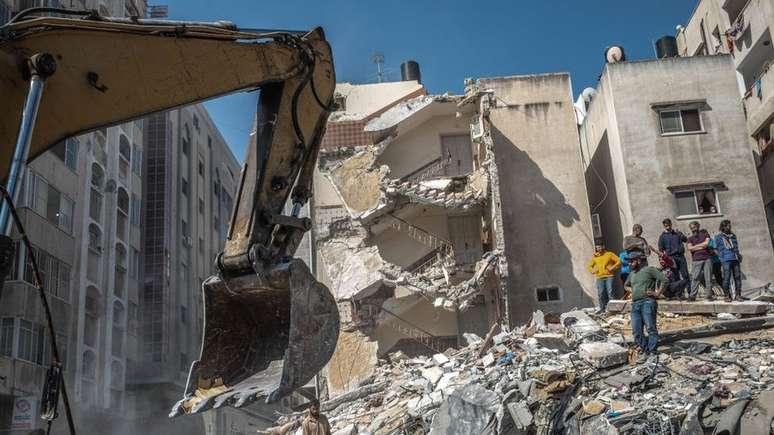 Palestinos inspecionam casa destruída, após ser atingida por ataques israelenses, na Cidade de Gaza, neste domingo