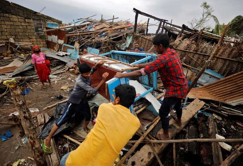 Pessoas resgatam seus pertences de uma casa danificada após passagem do ciclone Tauktae, na vila de Navabandar, no estado de Gujarat, oeste da Índia
18/05/2021 REUTERS/Amit Dave