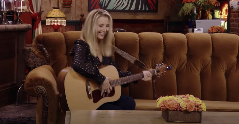 Lisa Kudrow com o famoso violão em que Phoebe Buffay tocava músicas com suas letras hilárias e por vezes constragendoras