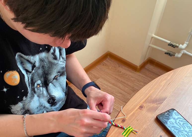 Nina fazendo uma pulseira da amizade para a m&atilde;e de Arina