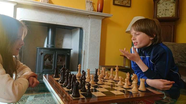 Focado pai e filho jogando xadrez na mesa antiga em hotel de luxo