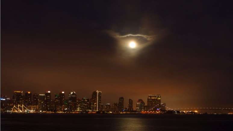 A superlua surge em nuvens acima da cidade de San Diego, Calif&oacute;rnia, EUA