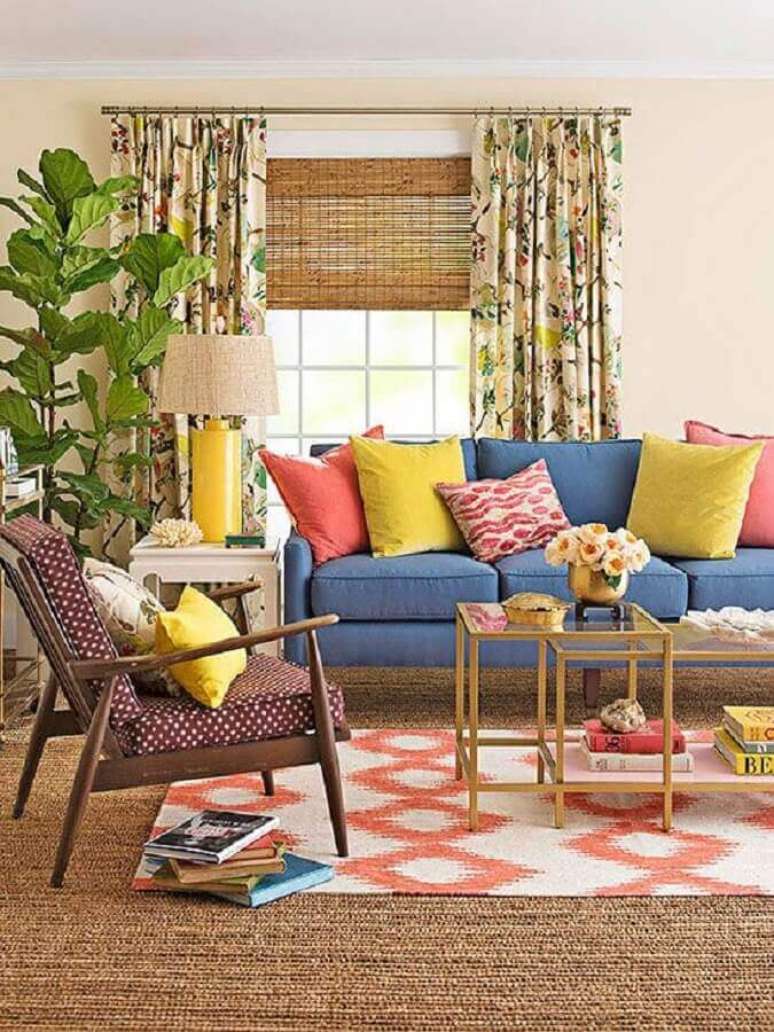 53. Almofadas coloridas para sofá azul em sala de visita simples decorada com poltrona de madeira – Foto: Better Homes and Gardens