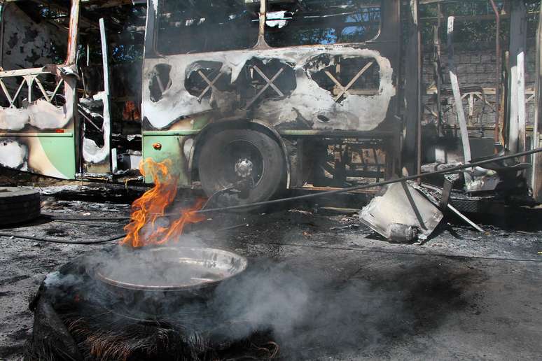 Funcionários de empresa de ônibus, trabalham para remover dois ônibus dos 14 que foram queimados por facções em ataques