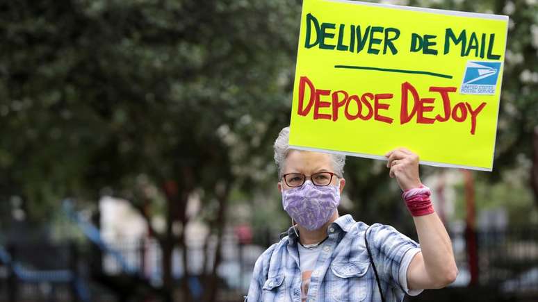 Mulher protesta em Washington com cartaz com os dizeres 'Entregue as correspond&ecirc;ncias/deponha DeJoy': administra&ccedil;&atilde;o de aliado de Trump foi alvo de cr&iacute;ticas