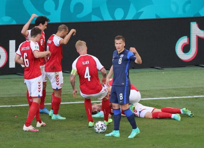 Jogador da Dinamarca Christian Eriksen, caído em campo, enquanto companheiros de equipe pedem socorro médico.  12/6/2021 Pool via REUTERS/Wolfgang Rattay