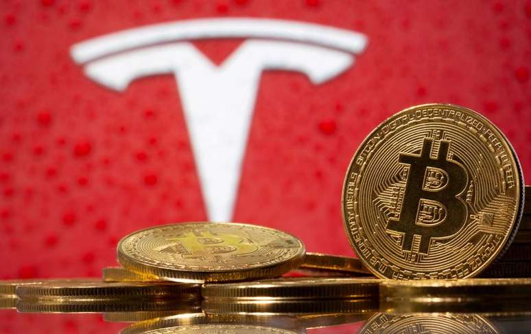 Representação da moeda virtual bitcoin tendo ao fundo o logotipo da montadora de veículos elétricos Tesla. 9/2/2021. REUTERS/Dado Ruvic