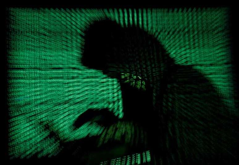 Imagem da silhueta de uma pessoa usando um laptop, tendo ao fundo códigos criptográficos. 13/5/2017.  REUTERS/Kacper Pempel