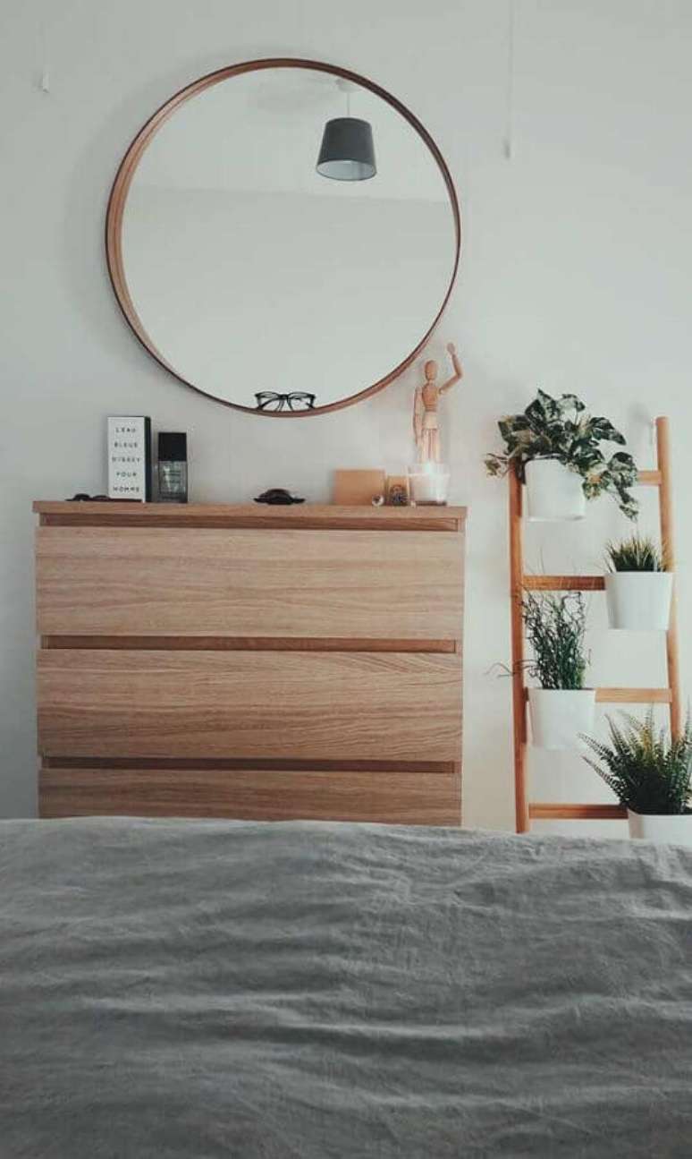 25. Cômoda para quarto decorado com espelho redondo e vasos de plantas – Foto: Apartment Therapy