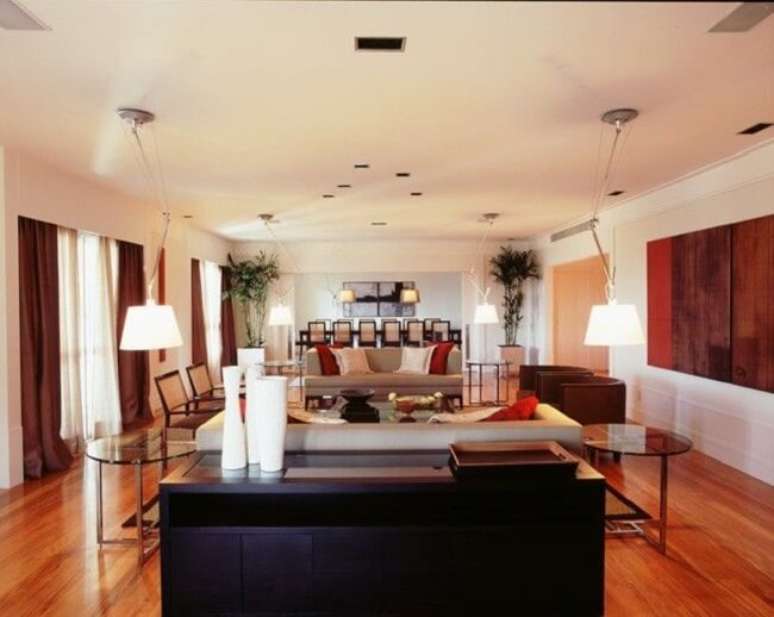 44. Aparador de madeira preto e mesas de vidro decoram a sala de estar. Projeto de Fernando Piva