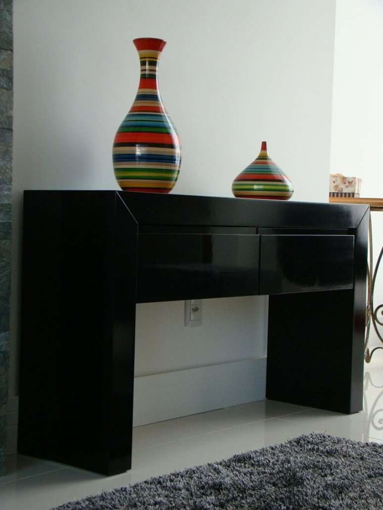 10. Os vasos coloridos trazem charme para o aparador preto com gaveta. Projeto de Carolina Wolfart