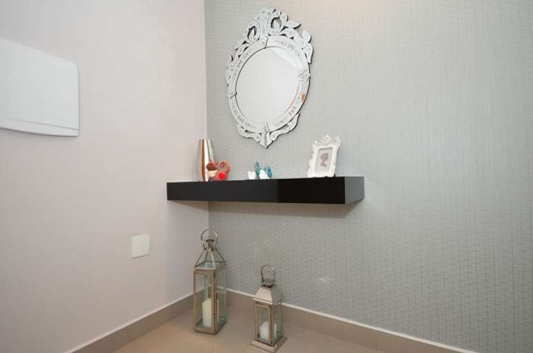 26. Hall decorado com aparador suspenso preto e espelho cl&aacute;ssico. Projeto de Condecorar Arquitetura e Interiores