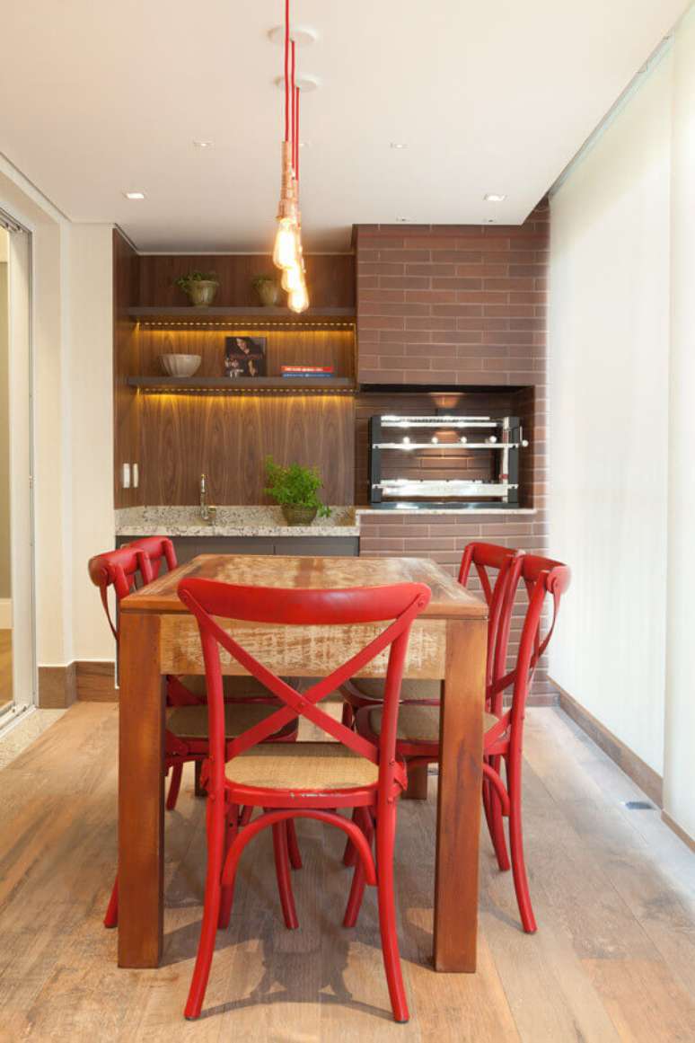 23. Modelo de área gourmet pequena decorada com cadeiras vermelhas para mesa de madeira – Foto: Liliana Zenaro