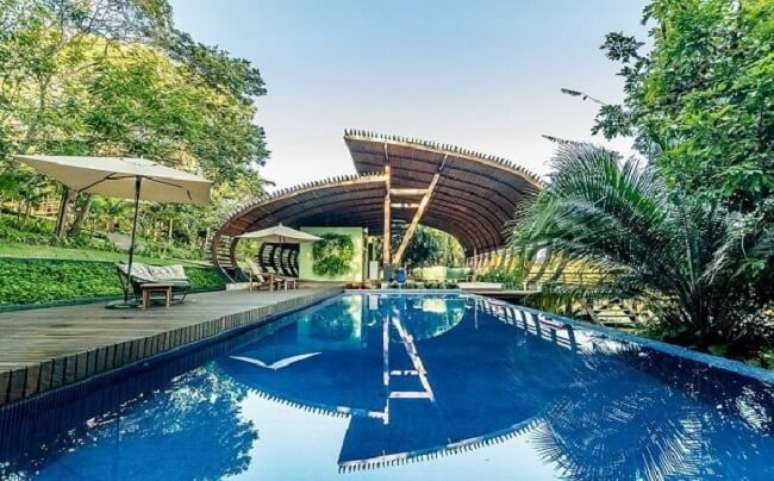 39. Piscina grande com deck de madeira e ombrelone de tecido. Fonte: Studio Clari&ccedil;a Lima