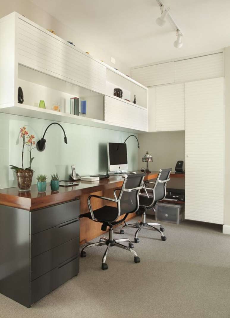 32. Ilumina&ccedil;&atilde;o de trilho branca, bancada de madeira e gaveteiro preto decoram o espa&ccedil;o. Projeto de Liliana Zenaro