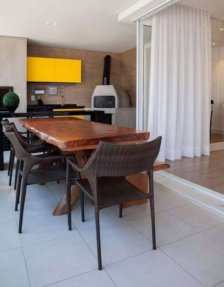 21. Modelo de área gourmet decorada com mesa de madeira rústica e forno de pizza – Foto: Jeito de Casa