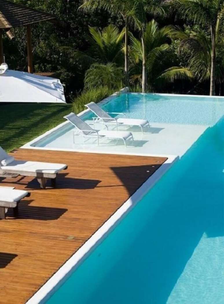 40. Piscina grande com deck e espregui&ccedil;adeiras com ombrelone. Projeto de SQ+ Arquitetos