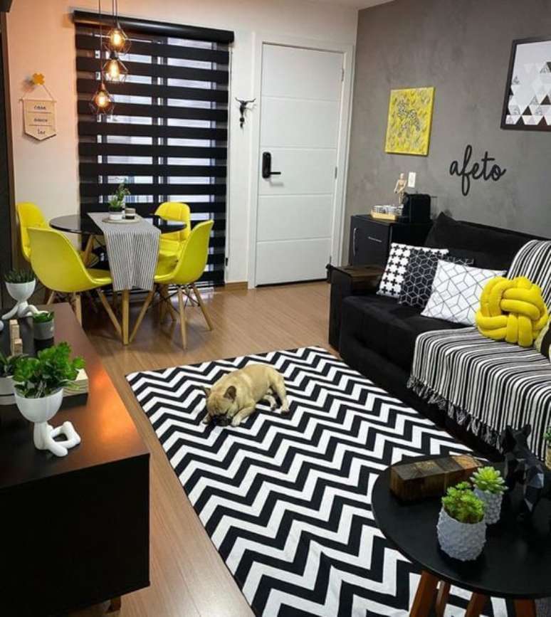 51. Sala com sofá preto, almofadas amarelas e tapete chevron – Foto Pinterest