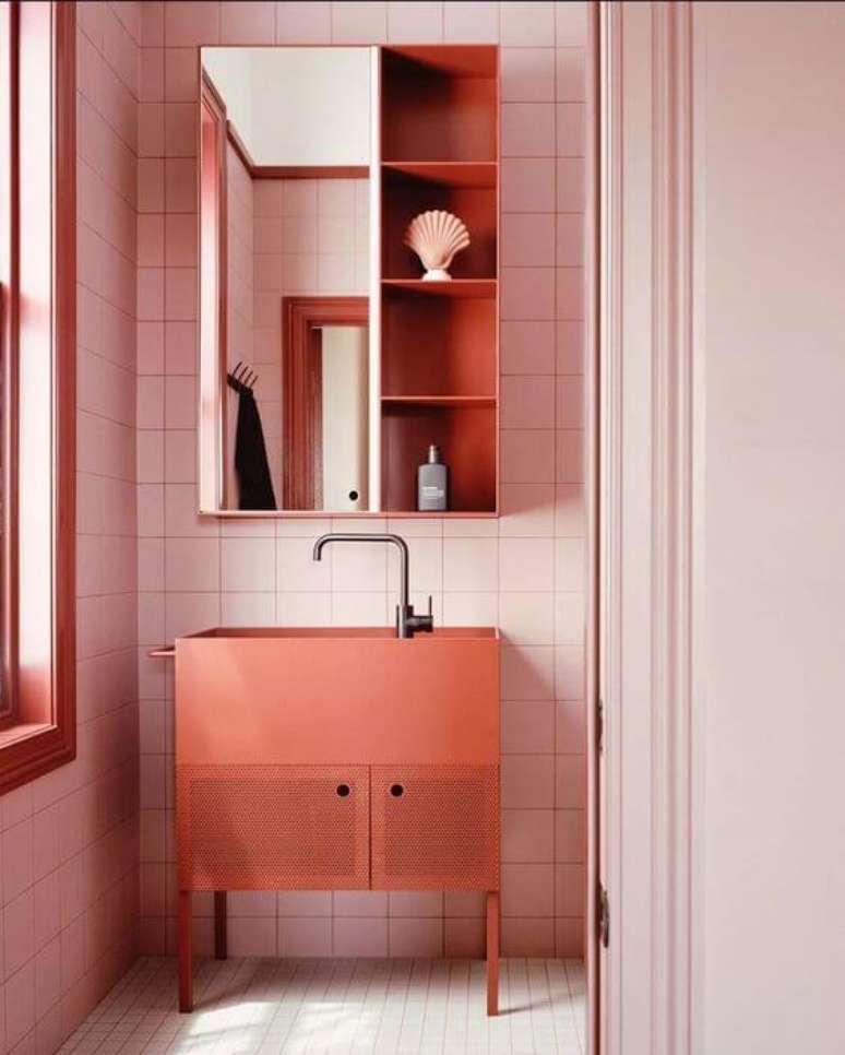 57. Banheiro decorado com gabinete na cor pessego e revestimento rosa claro – Foto Casa BVogue