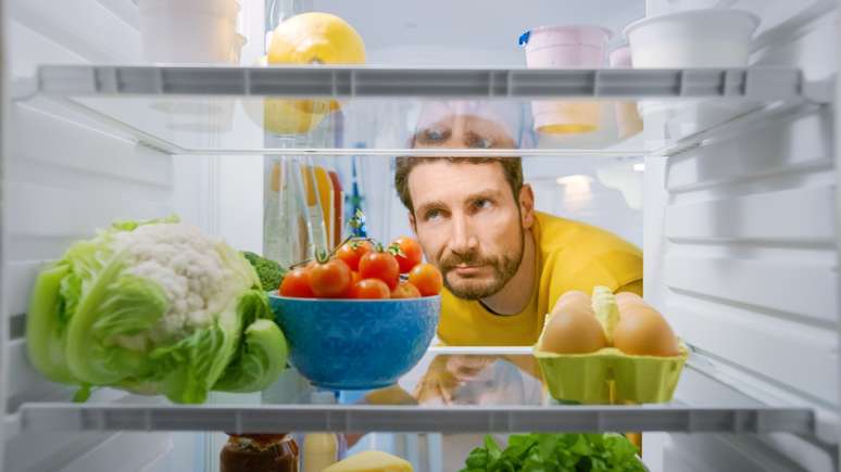 Homem olhando para dentro da geladeira