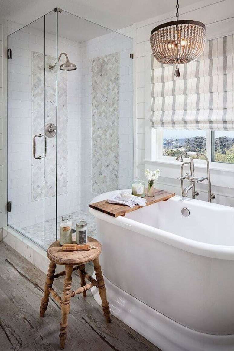 10. Banheiro com banheira decorado com piso rústico e lustre de teto – Foto: OneChitecture
