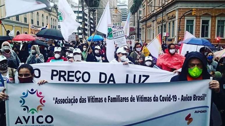 Paola e Gustavo seguram faixa da Avico durante protesto de 19 de junho