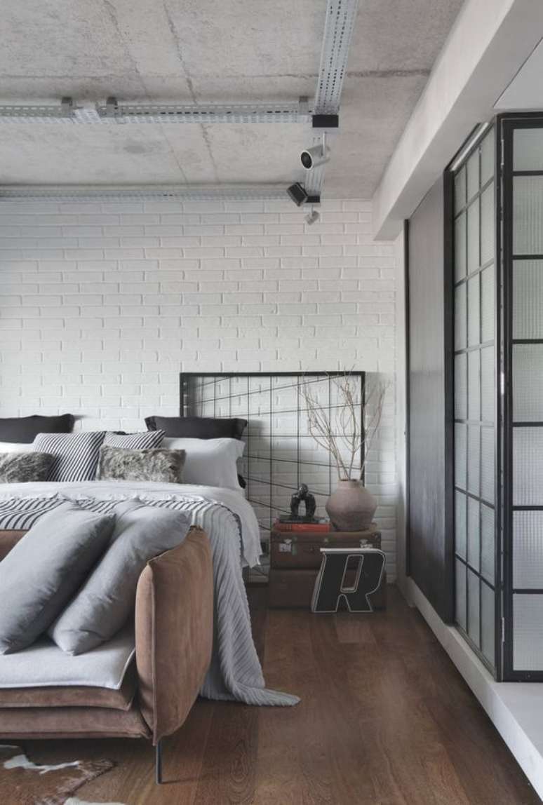 3. Quarto com piso marrom e sofá de couro na beira da cama – Foto Studio roca