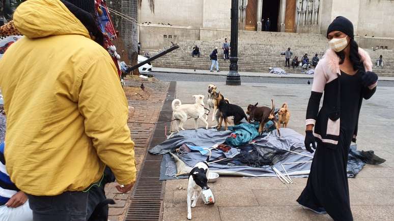 Natália ao lado dos cães que dormem na mesma barraca que ela na praça da Sé