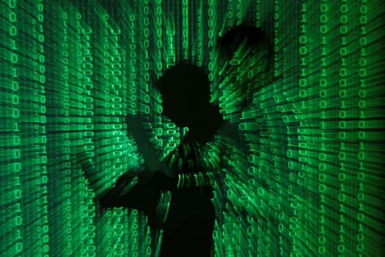 Projeção de códigos binários com homem no centro segurando um laptop
24/6/2013
REUTERS/Kacper Pempel