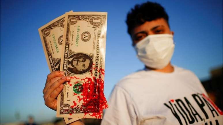 Manifestante exibe notas com rosto de Bolsonaro sujas de sangue em referência às denúncias de pedido de propina em contratos de compra de vacinas