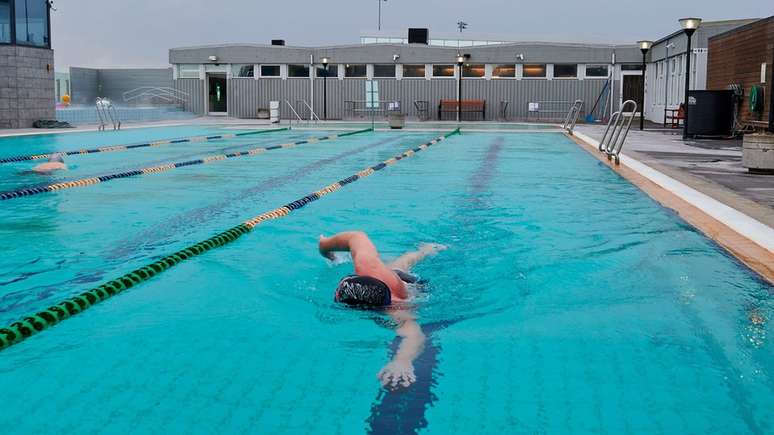 Homem nadando em piscina na Islândia