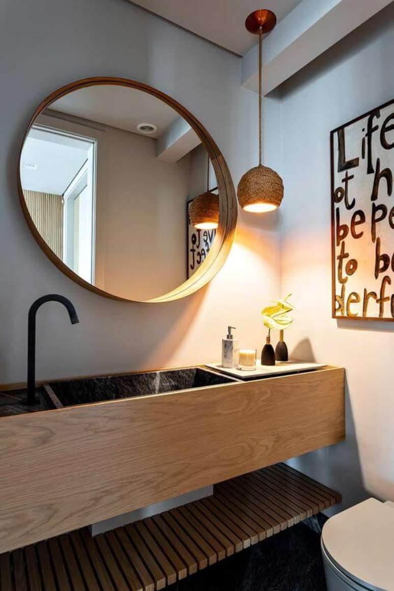 55. Banheiro com moldura redonda e gabinete de madeira – Foto Casa de Valentina