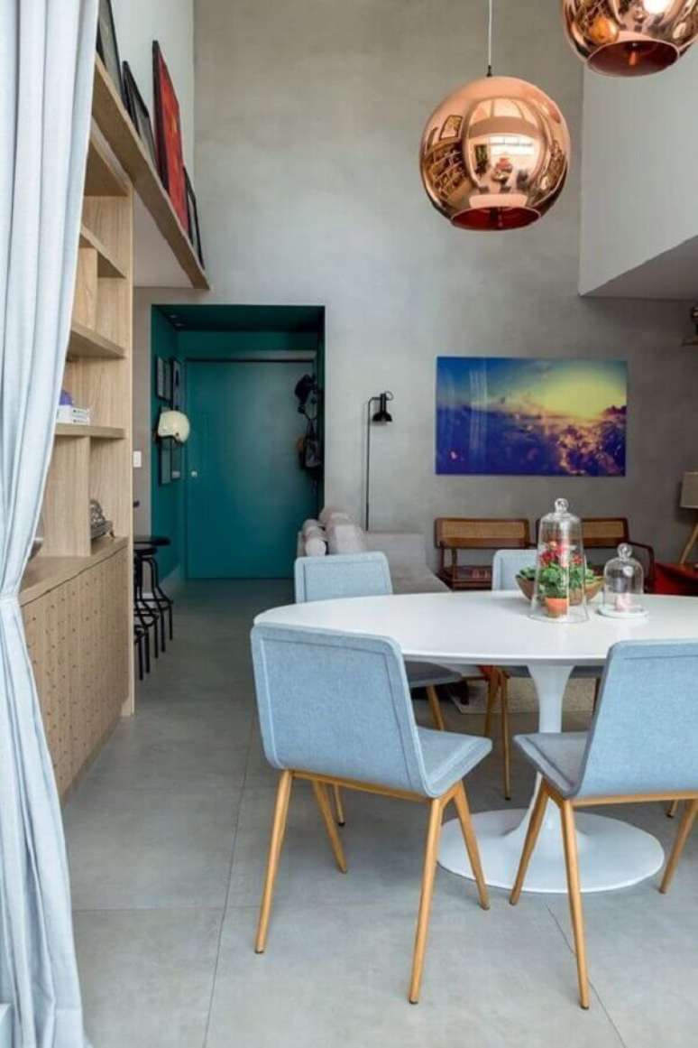 20. Cadeira azul claro para sala de jantar moderna decorada com mesa redonda e luminária rose gold – Foto: Histórias de Casa