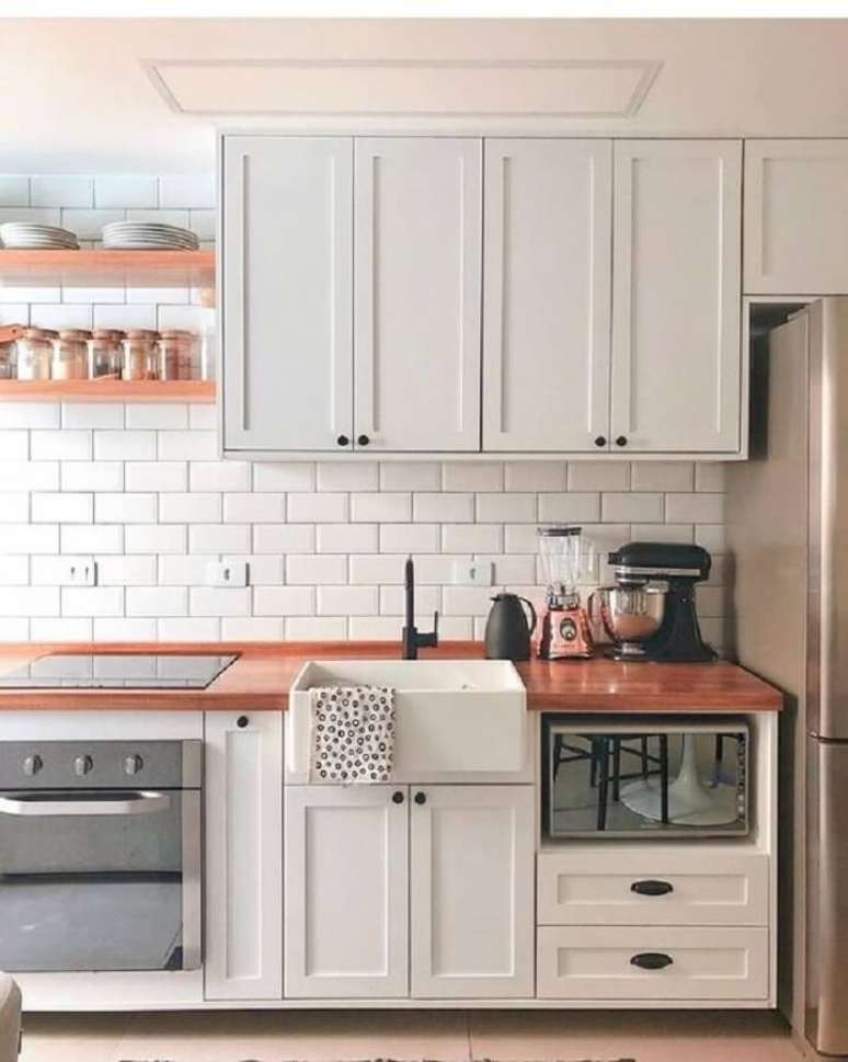 27. Cozinha branca decorada com armário vintage bancada de madeira e azulejo de cozinha branco simples – Foto Jeito de Casa