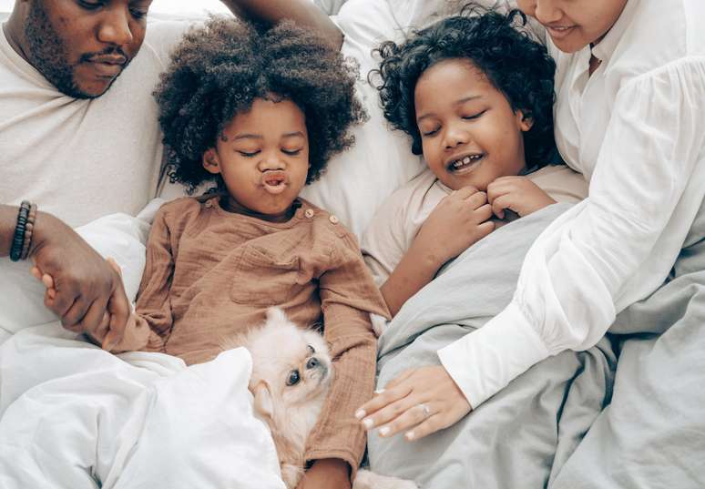 Família deitada na cama com cachorro