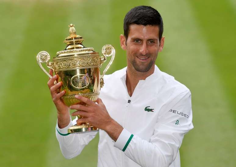 Novak Djokovic posa para foto ao lado do troféu de Wimbledon após conquistar o Grand Slam britânico em Londres
11/07/2021 REUTERS/Toby Melville